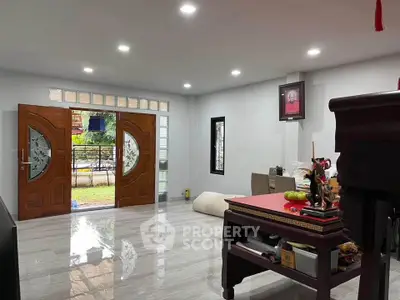 Spacious living room with elegant wooden doors and glossy tiled flooring, perfect for modern family living.