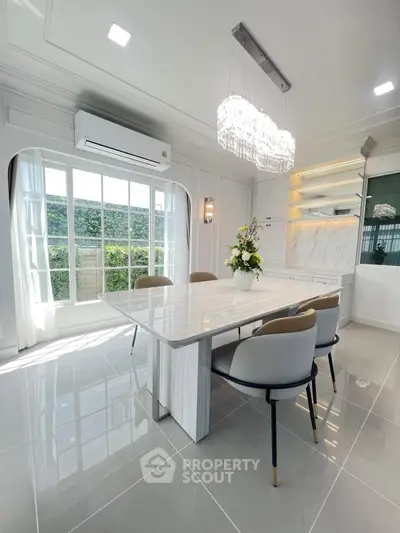 Elegant dining room with modern chandelier and large window overlooking lush greenery.