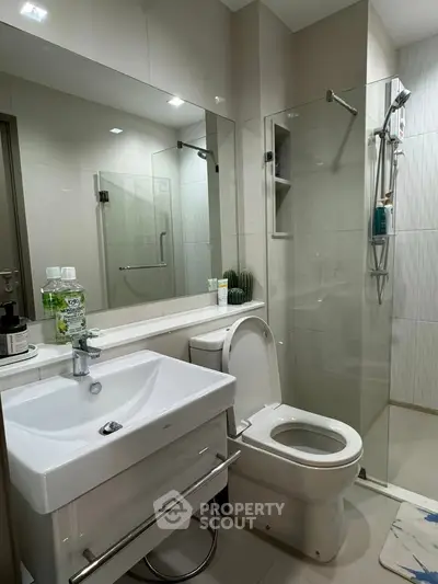 Modern bathroom with sleek fixtures and glass shower enclosure in a contemporary apartment.