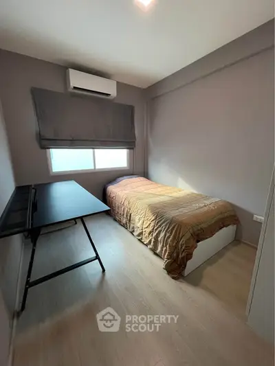 Cozy bedroom with single bed, desk, and air conditioning, perfect for a compact living space.