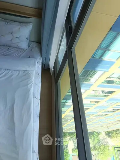 Modern bedroom with large window offering stunning city view in high-rise apartment.