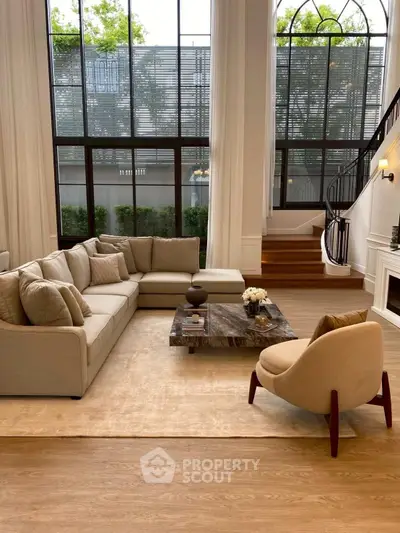 Luxurious living room with high ceilings, large windows, and elegant furniture in a modern home.