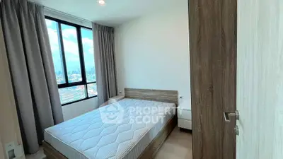 Modern bedroom with large window offering stunning city views, featuring minimalist design and cozy ambiance.