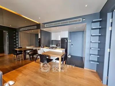 Modern open-layout kitchen with sleek design and dining area, featuring wooden flooring and stylish decor.