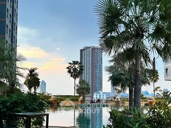 Luxurious poolside view with high-rise buildings and lush greenery at sunset.