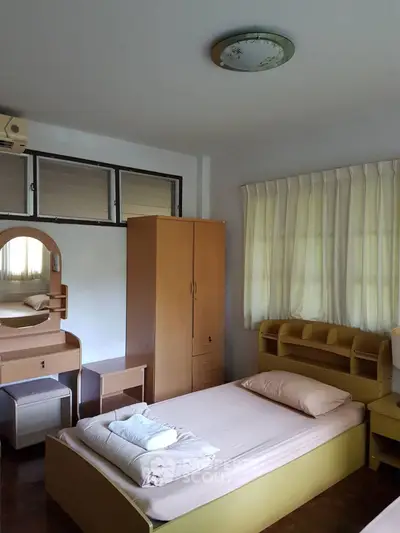 Cozy bedroom with wooden furniture and natural light, perfect for relaxation.