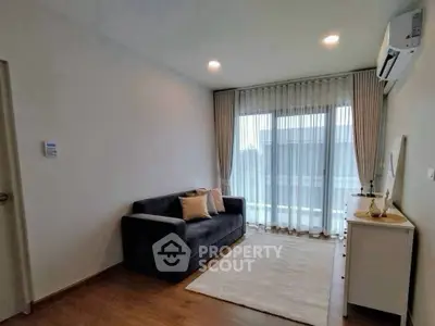 Modern living room with cozy sofa and large window, perfect for relaxation.