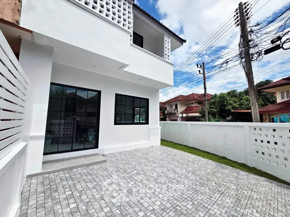 Modern white exterior of a two-story house with spacious paved driveway and lush green lawn.