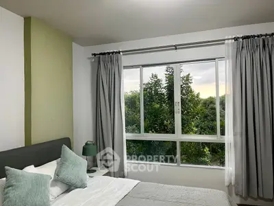 Cozy bedroom with large window offering lush green views and elegant decor.