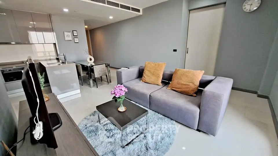 Modern living room with sleek gray sofa and open kitchen layout in stylish apartment.