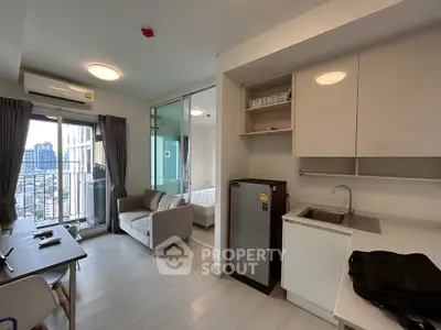 Modern apartment interior with open layout, featuring a compact kitchen, cozy living area, and city view balcony.