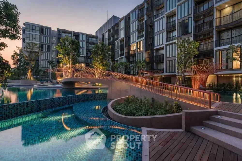 Luxurious modern apartment complex with stunning pool and landscaped gardens at sunset.