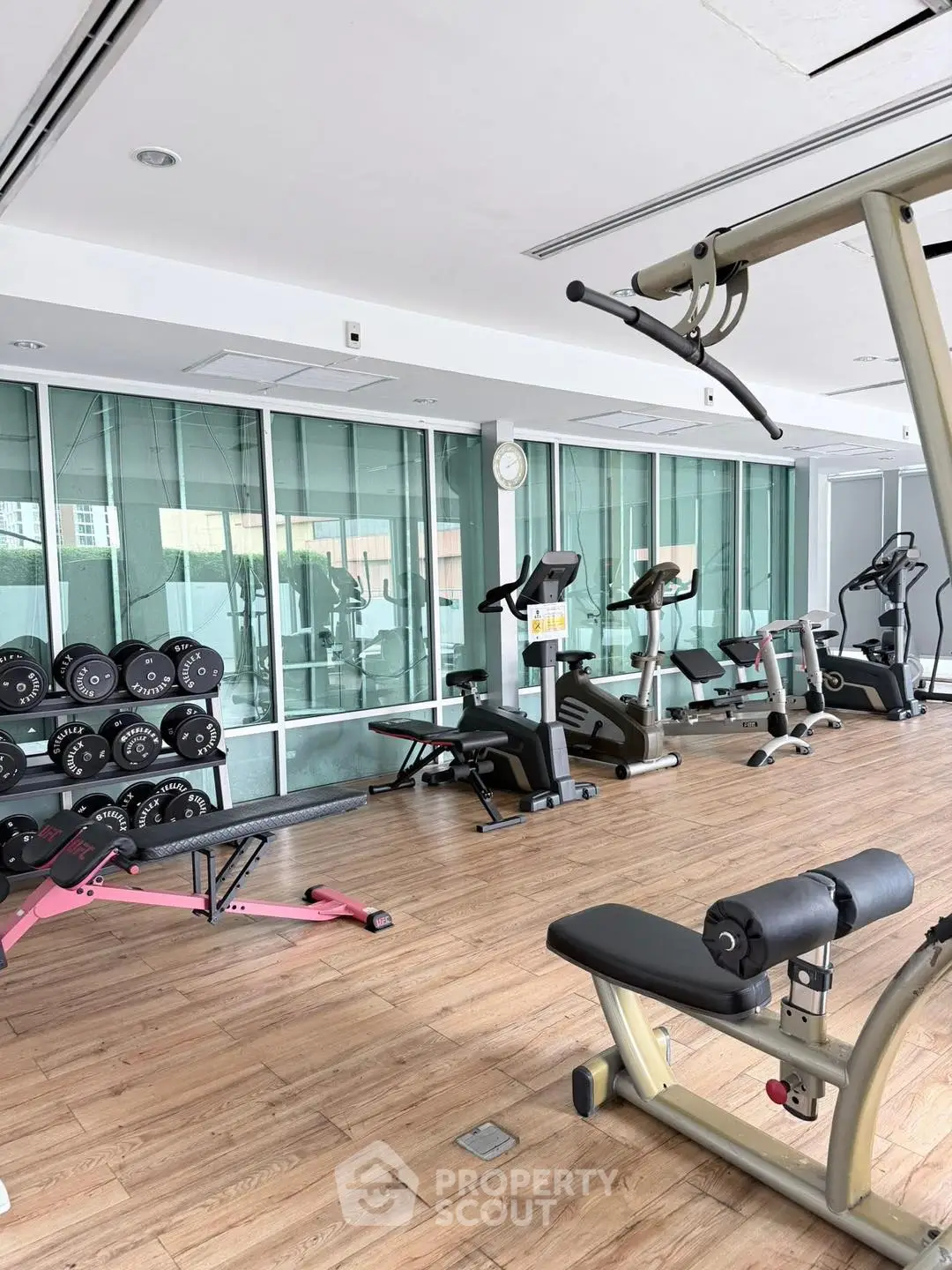 Spacious modern gym with state-of-the-art fitness equipment and wooden flooring.
