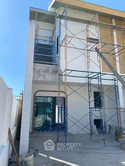 Modern house under construction with scaffolding and contemporary design.