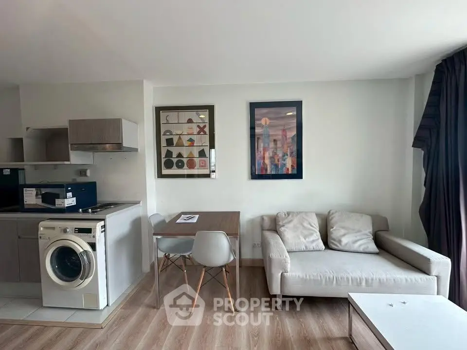 Modern living room with cozy sofa, dining table, and washing machine in open layout apartment.