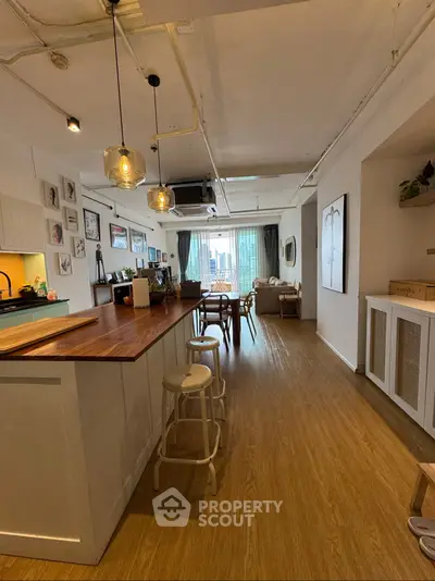 Spacious open-plan living room with modern kitchen and large windows offering city views.