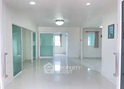 Spacious modern living room with white tiles and glass doors, perfect for family gatherings.
