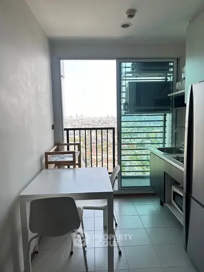Compact kitchen with city view, modern appliances, and dining area in high-rise apartment.