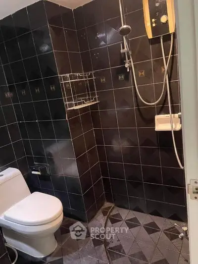 Modern bathroom with dark tiles and shower area in real estate property