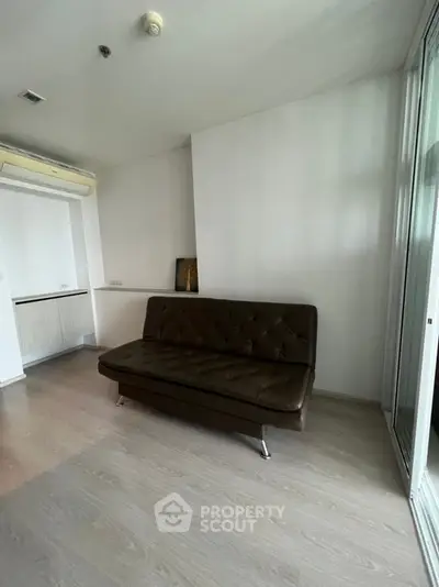 Modern living room with sleek brown sofa and minimalist decor, featuring large windows for natural light.