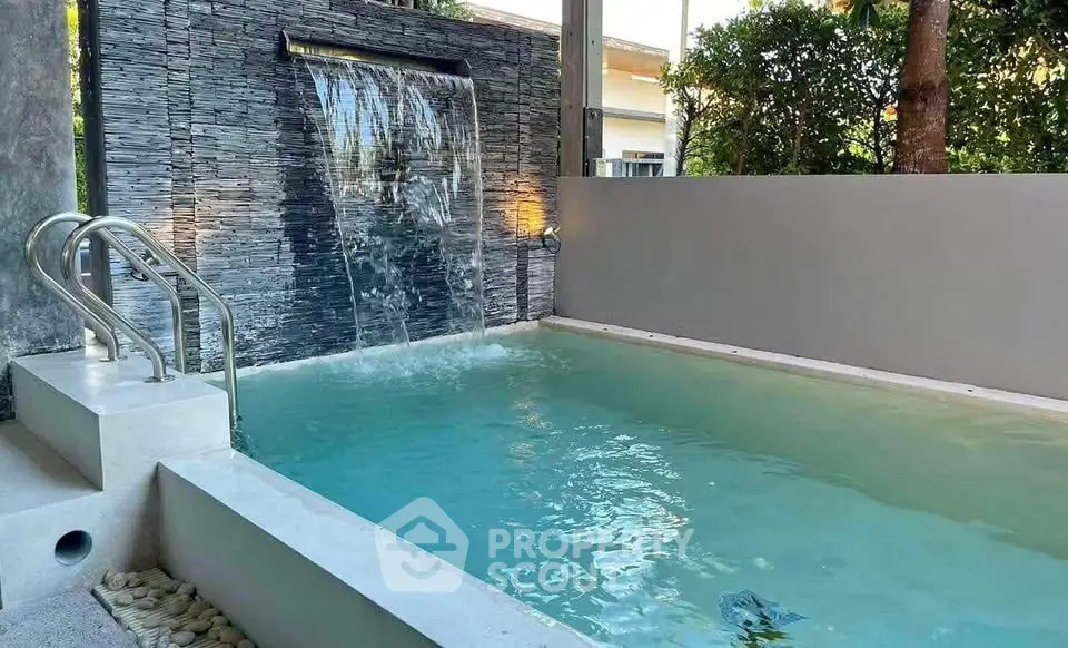 Luxurious private pool with waterfall feature in modern outdoor setting.
