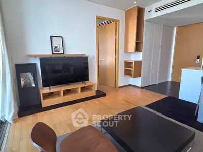 Modern living room with sleek wooden furniture and large TV, perfect for relaxation.