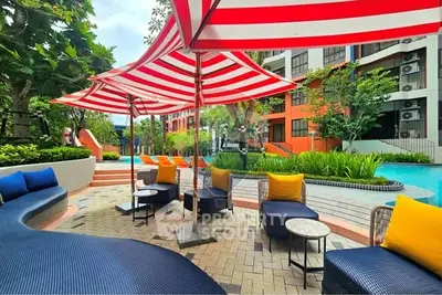 Vibrant outdoor pool area with colorful seating and striped umbrellas in modern residential complex.