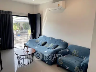 Cozy living room with modern sofa and air conditioning, featuring natural light and stylish decor.