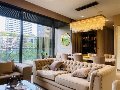 Luxurious living room with elegant chandelier and large windows offering stunning city views.