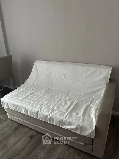 Cozy living room with a modern sofa covered in a white sheet, perfect for relaxation.