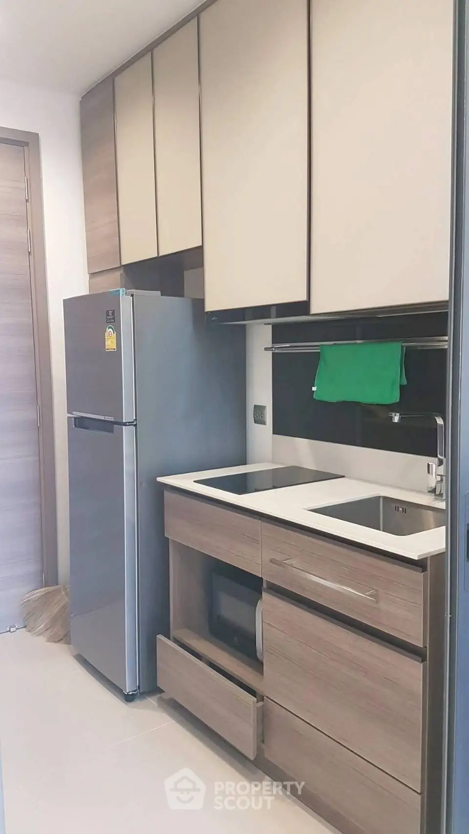 Modern compact kitchen with sleek cabinetry and stainless steel fridge