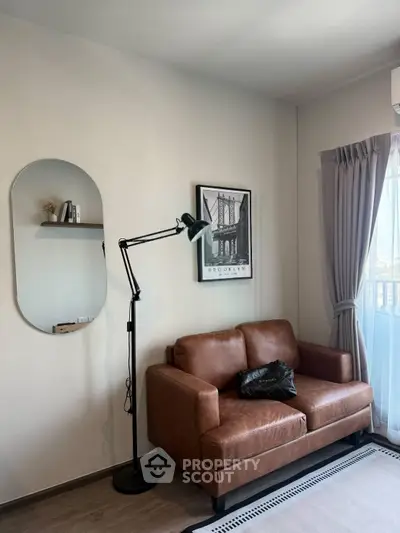 Stylish living room with leather sofa, floor lamp, and modern decor in a cozy apartment.