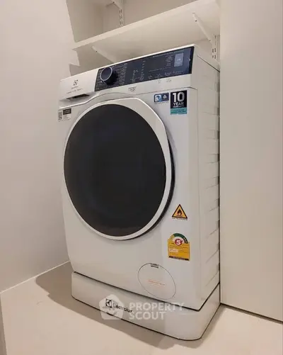 Modern Electrolux washing machine in sleek laundry area with ample storage space.