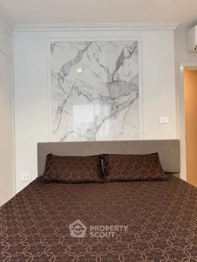 Modern bedroom with stylish marble accent wall and cozy bedding