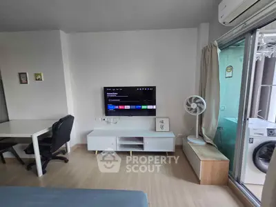 Modern living room with TV, desk, and washing machine in a compact apartment.