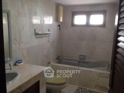Spacious bathroom with marble tiles and a built-in bathtub, offering a serene and elegant ambiance.