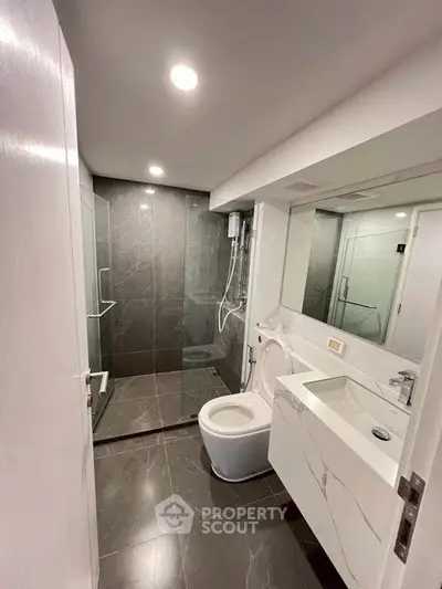 Modern bathroom with sleek design, featuring a glass shower and elegant fixtures.