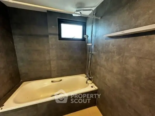 Modern bathroom with sleek bathtub and dark tiled walls