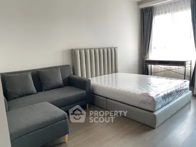 Modern bedroom with stylish bed, cozy sofa, and natural light from large window.