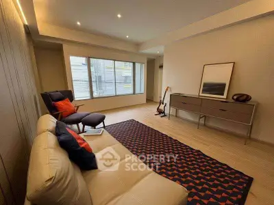 Modern living room with stylish furniture and large window offering natural light.
