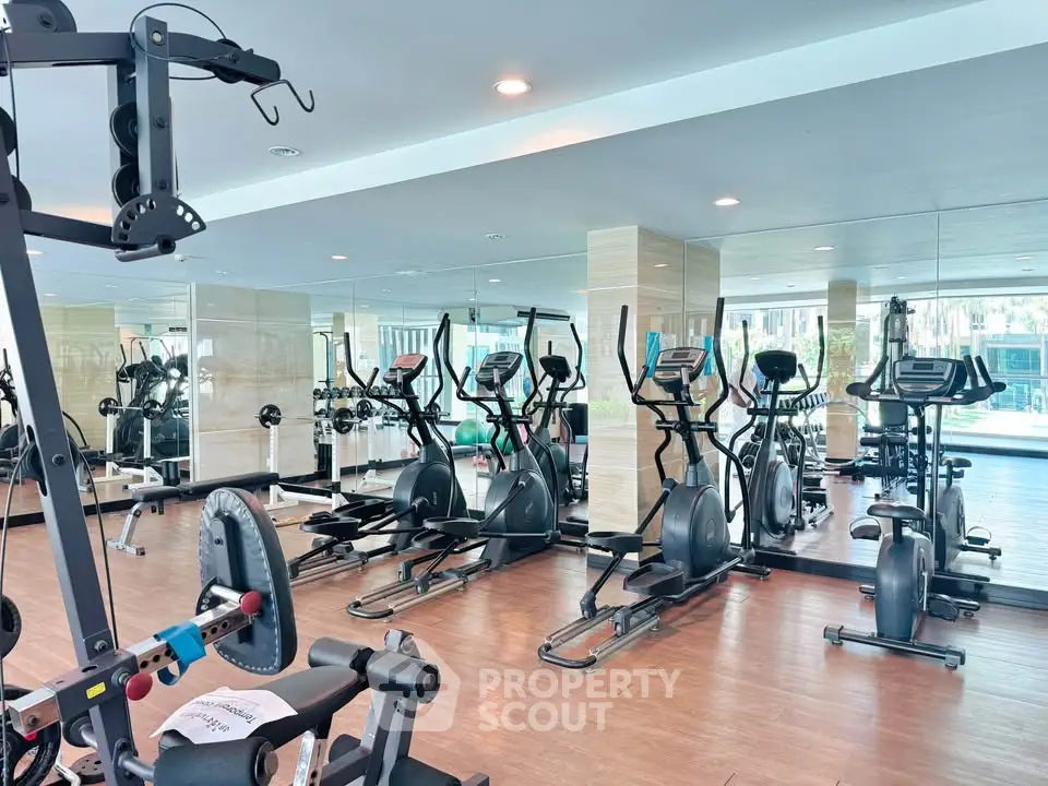 Spacious modern gym with state-of-the-art fitness equipment and mirrored walls in a luxury residential building.