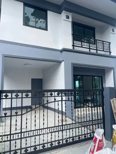 Modern two-story house with sleek balcony and gated entrance, showcasing contemporary architecture.