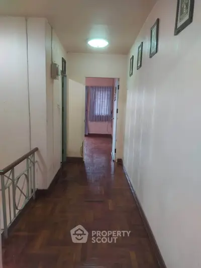 Spacious hallway with wooden flooring leading to a bright room, perfect for a cozy home ambiance.