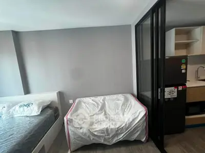 Modern apartment interior with bed, sofa, and kitchen area, featuring sleek design and practical layout.