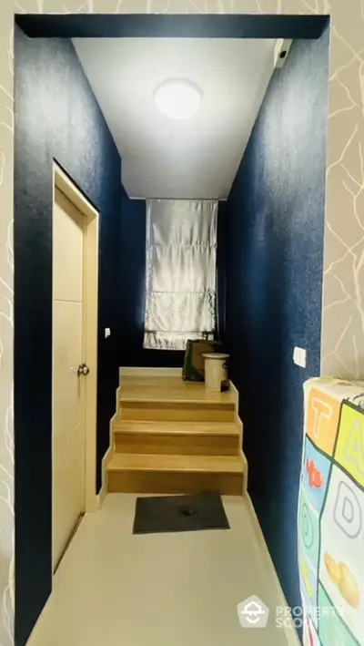 Modern hallway with stylish dark blue walls and wooden stairs