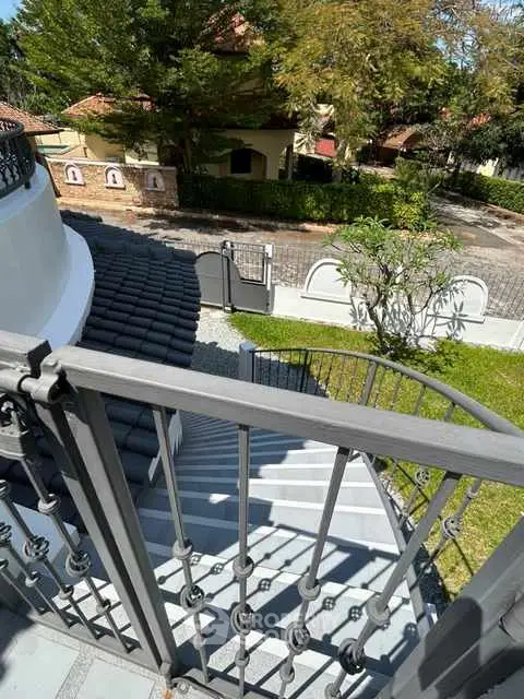 Elegant exterior staircase with wrought iron railing leading to a charming garden view.