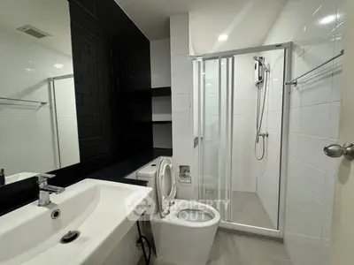 Modern bathroom with sleek black and white design, featuring a shower and contemporary fixtures.