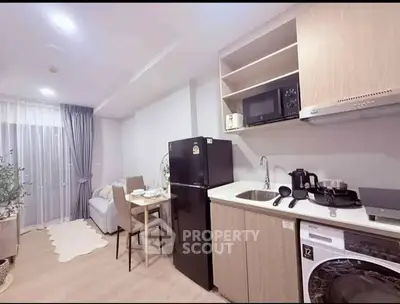 Modern open-layout kitchen with dining area and cozy living space, featuring sleek appliances and stylish decor.