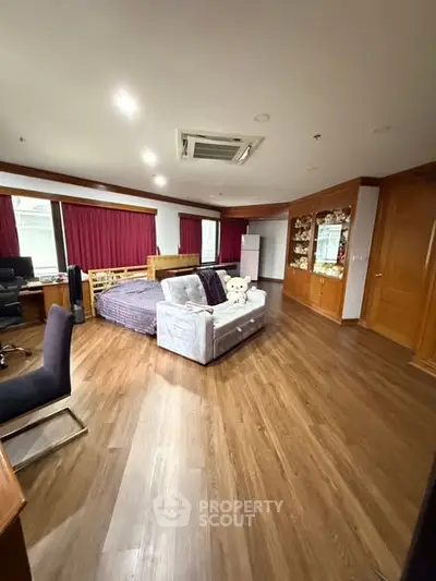 Spacious bedroom with wooden flooring and cozy seating area