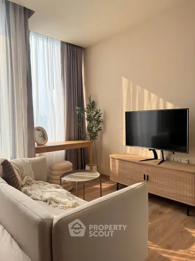 Stylish living room with modern decor, large window, and flat-screen TV, perfect for relaxation.